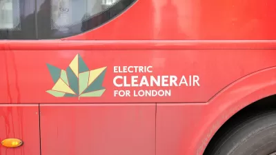 Close-up of geometric green leaf logo and "Electric Cleaner Air for London" white text on side of red London bus.