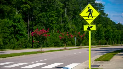 Yellow pedestrian caution sign next to a zebra crosswalk.