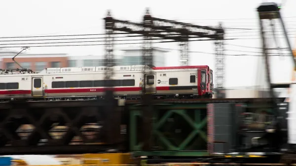 White and red train speeding past on green elevated bridge in Norwalk, Connecticut.