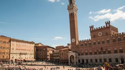 Busy plaza in Siena, Italy with prominent clock tower.