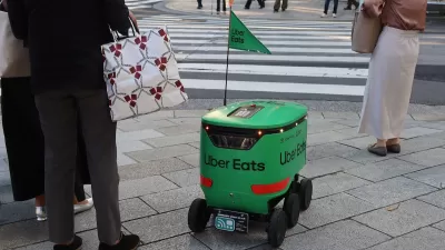 Green Uber Eats delivery robot waits at crosswalk in Tokyo, Japan.