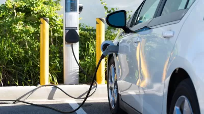 White electric car being charged in parking lot.