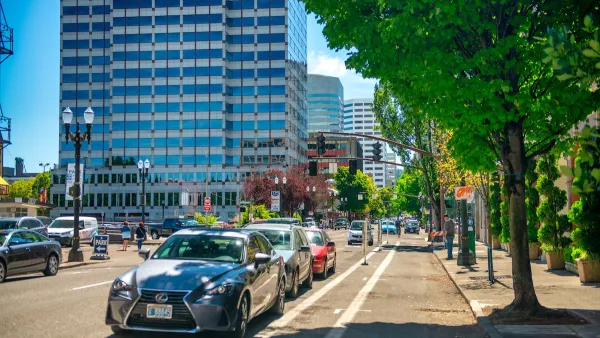Street with parking protected bike lane and parked cars in downtown Portland, Oregon.