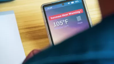 Close-up over shoulder of person holding smartphone with extreme heat warning and 105 degree temperature indicated.