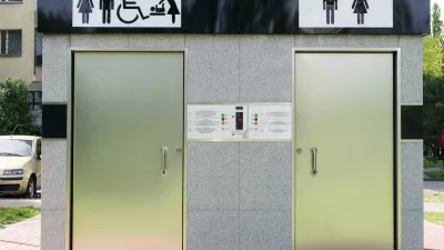 Outdoor public restrooms with two silver doors and icons for men, women, wheelchair accessibility, and baby changing above doors.