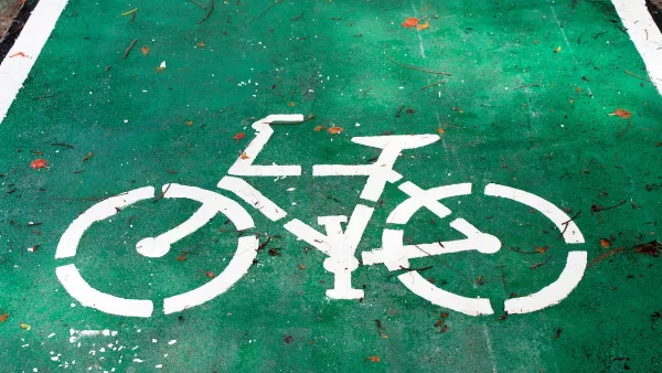 White bike symbol painted on green bike lane.
