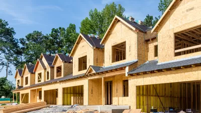 Wood-frame two-story rowhouses under construction.