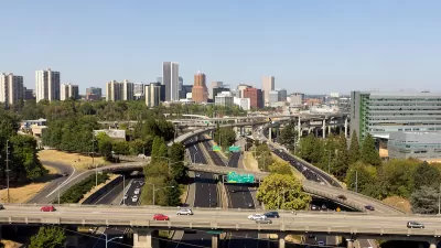 Aerial view of highway overpasses with Portland, Oregon skyline in background.