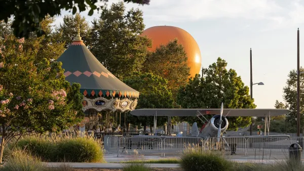 Afternoon light illuminates the landscape with orange tethered hot air balloon, vintage airplane, and carousel at Great Park in Irvine, California.