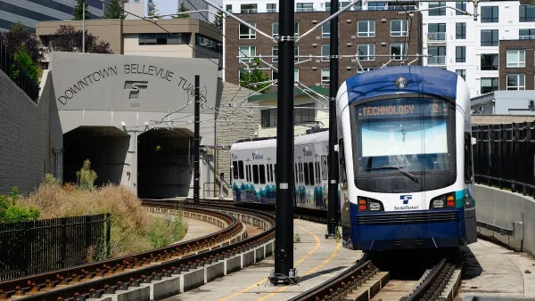 Blue and white Seattle Link light rail train exiting concrete Downtown Bellevue Tunnel in Bellevue, WA.