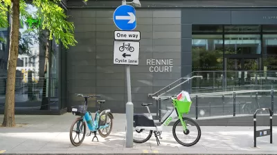 Two electric dockless bikes parked on sidewalk in London, UK.