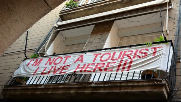 Banner reading "I'm not a tourist - I live here!!!" hung on balcony in Barcelona, Spain.