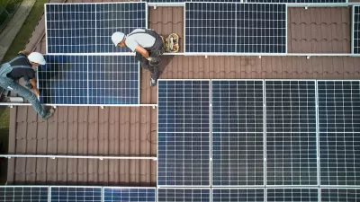 Bird's eye view of workers installing solar panels on rooftop.