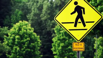 Yellow 'Yield to pedestrians' sign with graphic sign of person walking across street.