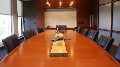 Large brown wood conference table surrounded by black leather chairs.