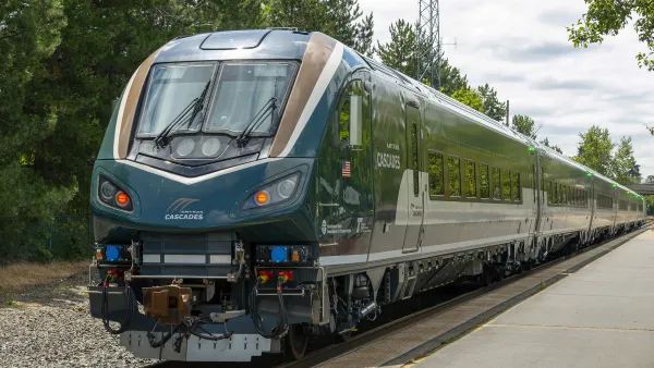 An Airo train driving towards the camera on a track. There is a forest behind it.