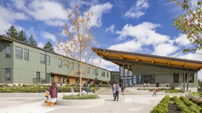 Green u-shaped school building with slanted roof and courtyard in the middle