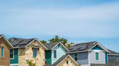 A row of homes, some brightly colored, on a sunny day in Austin, Texas.