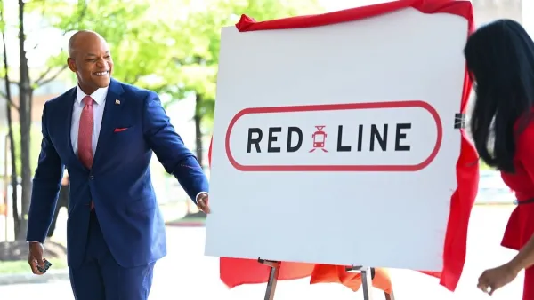 Maryland Governor Moore stands in front of a board with "Red Line" train logo.