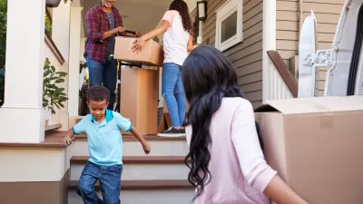 A family of Black Americans brings moving boxes into a home.
