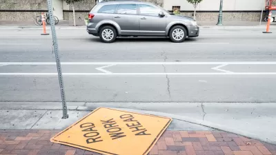 A "Road Work Ahead" lies neglected on the ground next to a street in Boise, Idaho.