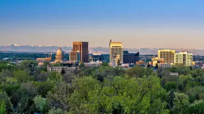 A view of the Boise skyline, across tress int he foreground. The state capitol is visible amongst other office buildings.