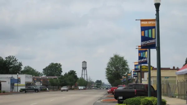 Wide, empty street with decorative town banners on light posts and water tower in background in West Memphis, Arkansas.