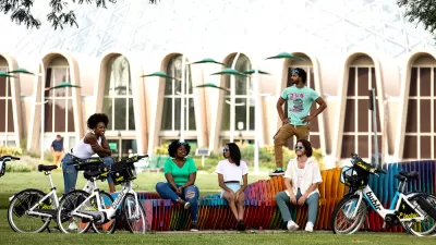 Promotional photo of diverse group of young people sitting on colorful bench with their Bublr bike share e-bikes parked in front of them.