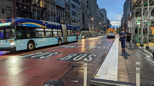 Blue and turquoise New York City bus at night on a red painted bus lane.