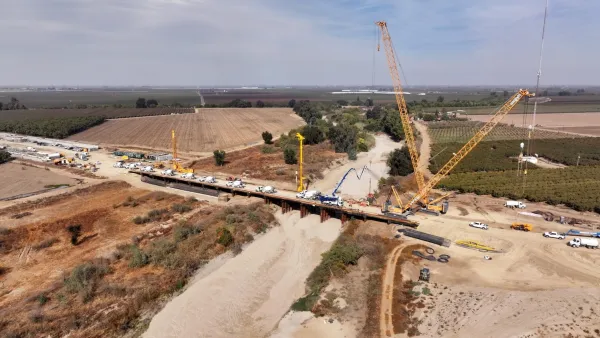 Bridge over dry wash for California High-Speed Rail train with tall yellow construction crane in Central Valley, California.