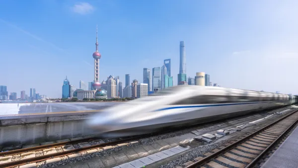 A high-speed rail is blurred as it passes a modern skyline in China.