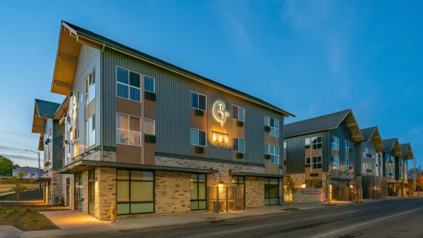 Three-story apartment complex with pitched roofs at dusk.