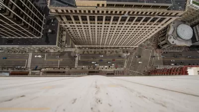 A busy urban street is seen from the vantage point offered by looking straight down from the top of a high-rise.
