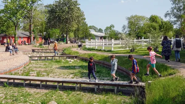 Children walking on a wooden walkway over green creek bed in Copenhagen, Denmark.