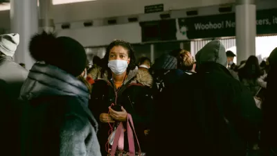 A woman wears a mask during the Covid-19 pandemic in a large crowd at a transit station in New York City.