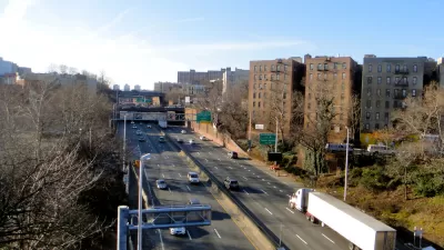A view of the Cross Bronx Expressway, an elevated highway that allows cars to drive past apartment buildings.