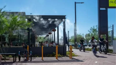 People ride bikes past outdoor restaurant patio with misters in Culdesac car-free development, Tempe, Arizona.