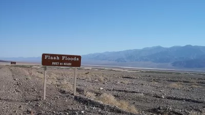 Brown and white "flash floods: next 55 miles" road sign in Death Valley, California