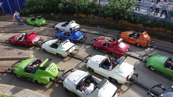 Aerial view of several multicolored Autopia cars on tracks with riders in Disneyland.