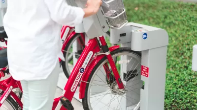 Close-up of person checking out bike at Houston BCycle station with red bikes