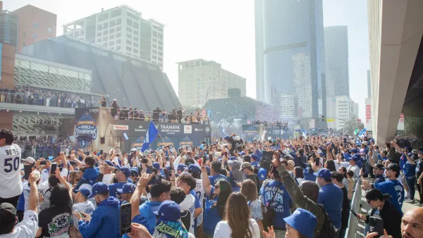 Crowd of LA Dodgers fans in downtown Los Angeles waving pennants, celebrating a win.
