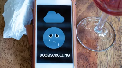 A mobile phone with a crying emoji face and the word "doomscrolling" is on a table between a tissue and a glass of wine.