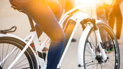 An electric bicycle is shown with the legs of a human who is riding the e-bike.