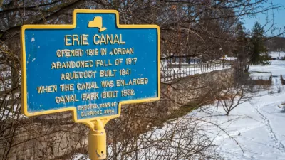 A commemorative plaque documents the history of the Erie Canal: Opened in 1819, abandoned fall of 1917, an extra aqueduct built in 1841 to expand the canal, and a canal park built in 1932.