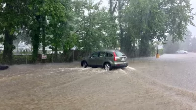 A sports utility vehicle drives throw brown floodwaters that have inundated the entire area depicted in the picture.