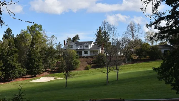 Large house on golf course in Los Altos Hills, California with blue sky with fluffy clouds.