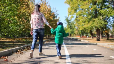Parent and child walking, holding hands on mixed-use trail with trees