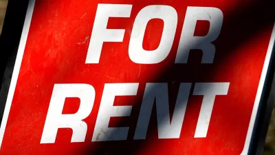 Close-up of FOR RENT sign with white text on bright red background.