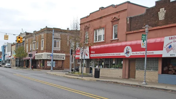 Brick buildings on small town street with red awnings on first floor businesses.