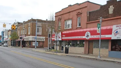Brick buildings on small town street with red awnings on first floor businesses.